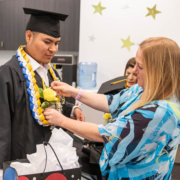 Staff pinning corsage on student's graduation gown