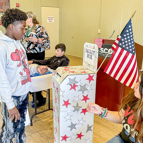 Student casting his ballot and receiving an I Voted sticker