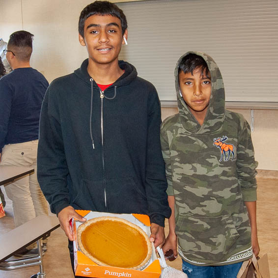 Students holding grocery bags and a pumpkin pie