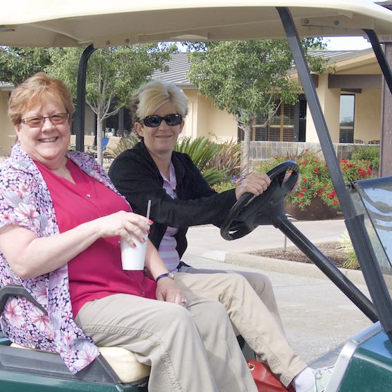 Staff riding in golf cart, drinking soda