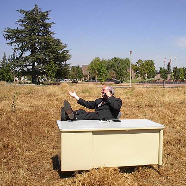 Dr. Meaney sitting at a desk, talking on a landline phone in the middle of an empty field