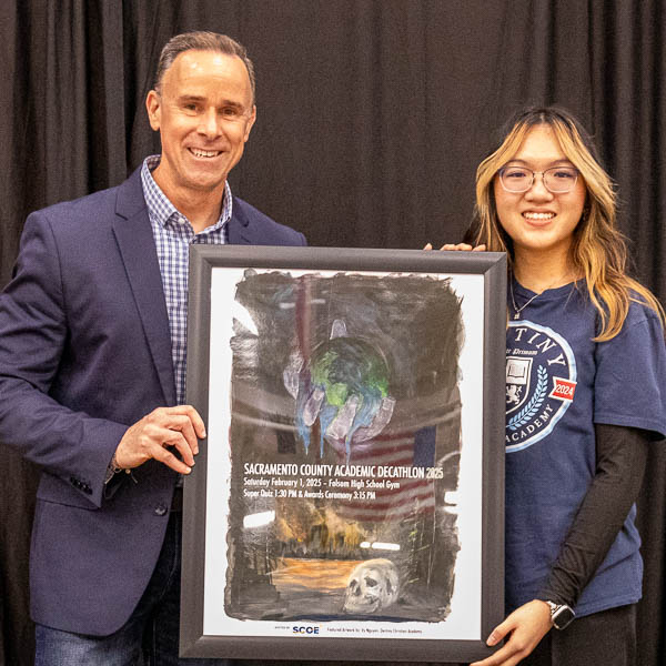 Craig Irish and Vy Nguyen holding framed poster