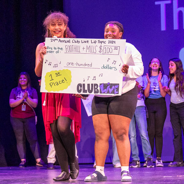 Students on stage holding large check
