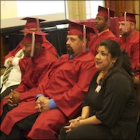 Seated graduates wearing red caps and gowns