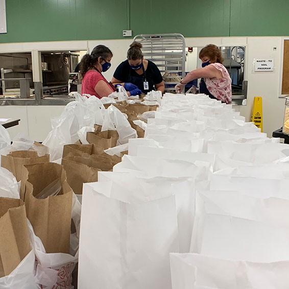 Sly Park kitchen staff, wearing masks, prepare bagged student meals