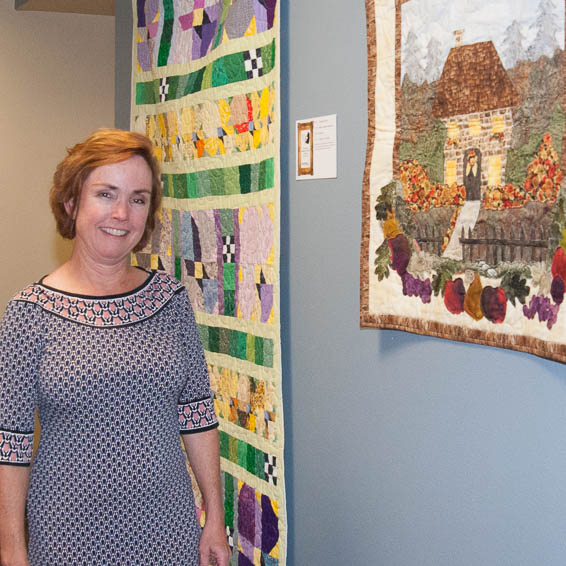 Employee posing in front of hanging quilts