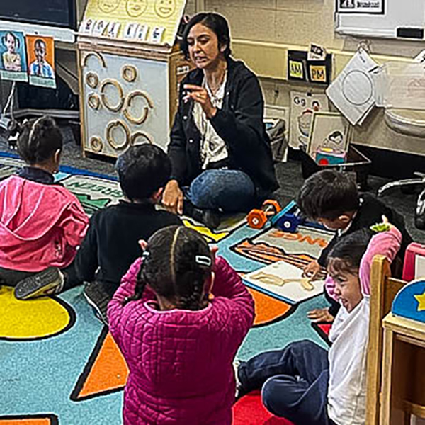 Teacher seated on floor in front of children