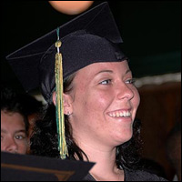 Graduate in cap and gown smiles during graduation ceremony