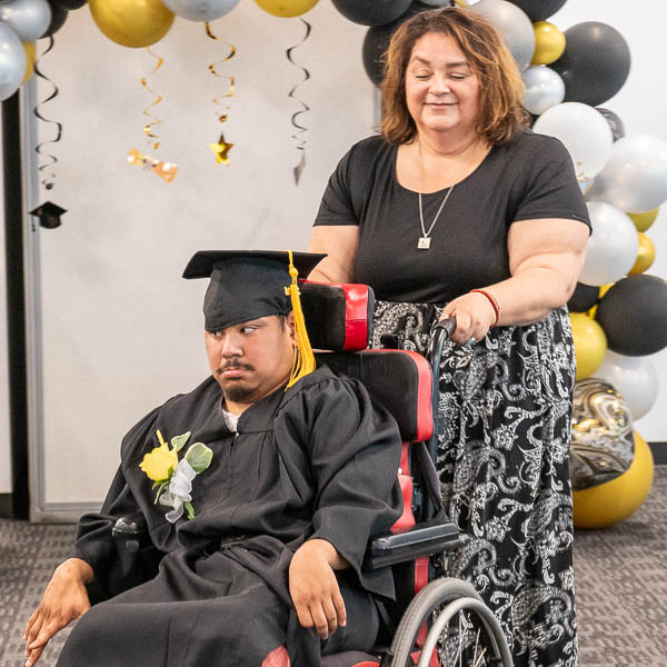 Staff pushing graduate using wheelchair