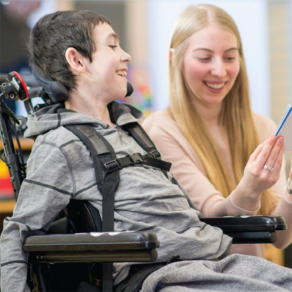 Para-professional educator reading with a student who is using a wheelchair