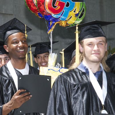 Cap and gown clad students holding diplomas