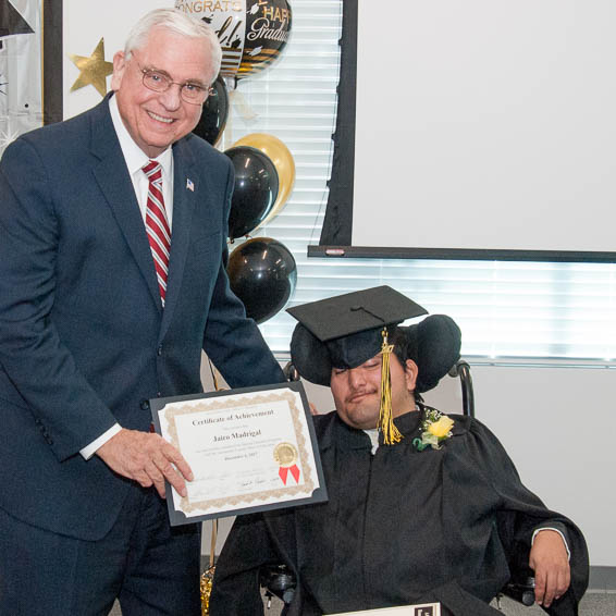 Superintendent Gordon presenting certificate to student using wheelchair