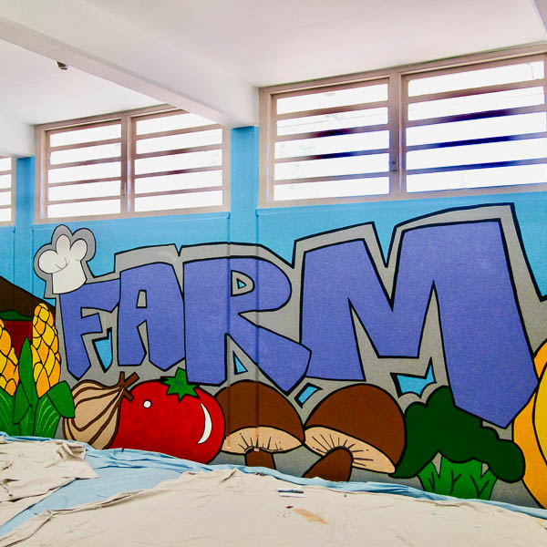 The letters FARM on a wall, surround by painted vegetables