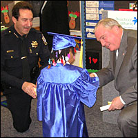 Superintendent and Police Chief kneeling to congratulate a student