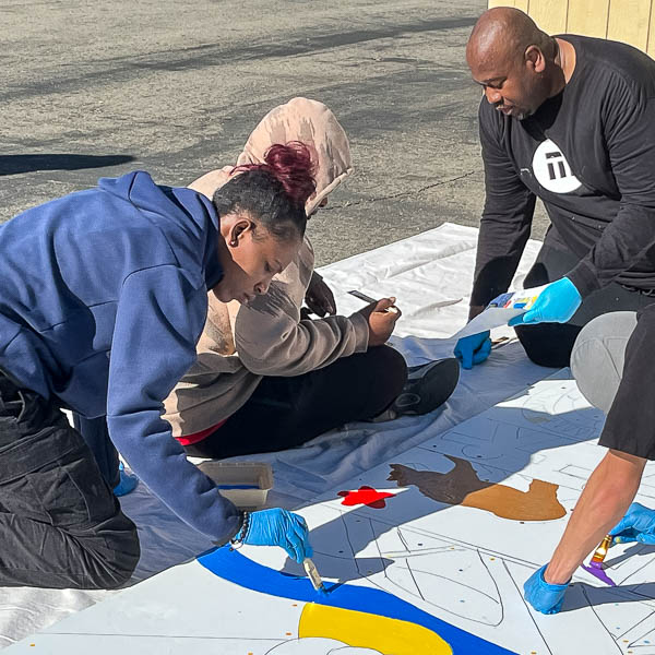 Milton Bowens helping students as they paint a mural