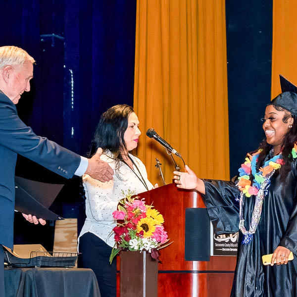 Dave Gordon shaking hands with a graduate