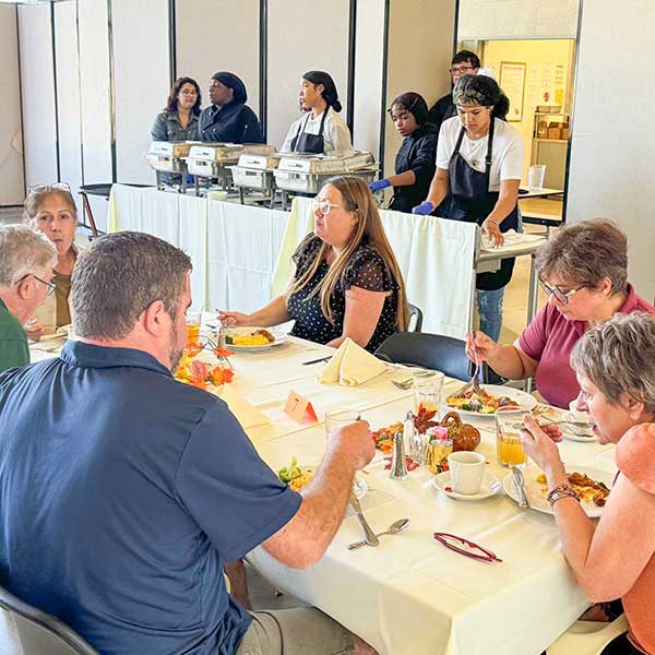 Guests eating with students serving in background