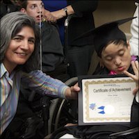 Board member presenting certificate to student using wheel chair