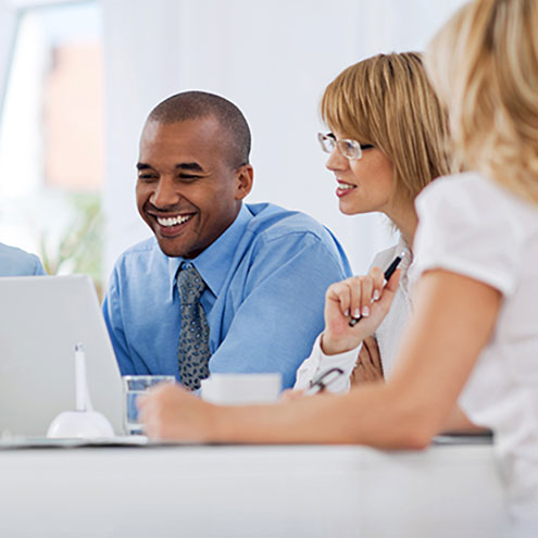 Smiling adults seated around a laptop