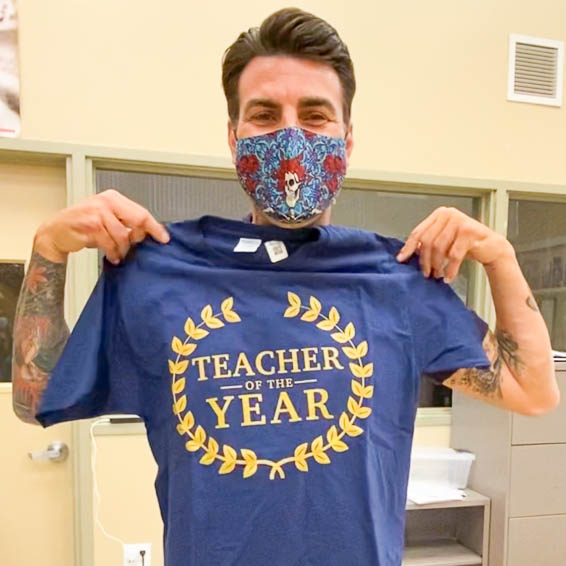 Nick Papagiannopoulos holding up Teacher of the Year t-shirt
