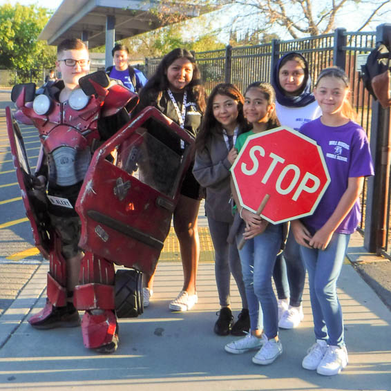 Student dressed as a car posing with peers holding a stop sign